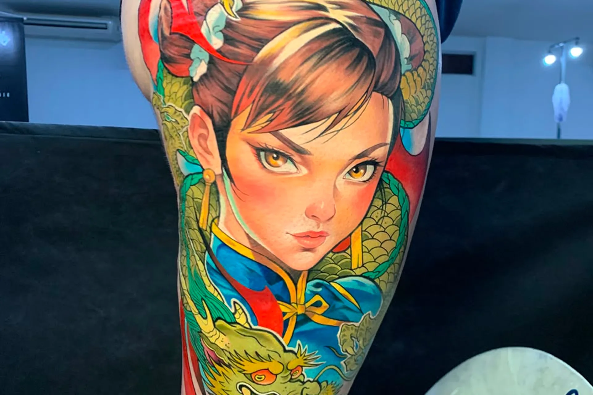 Tatuagem colorida de personagem com dragão verde, feita pelo Ramon